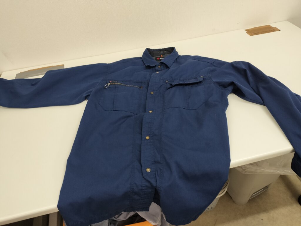 テーブルに広げられた青色の長袖作業シャツ