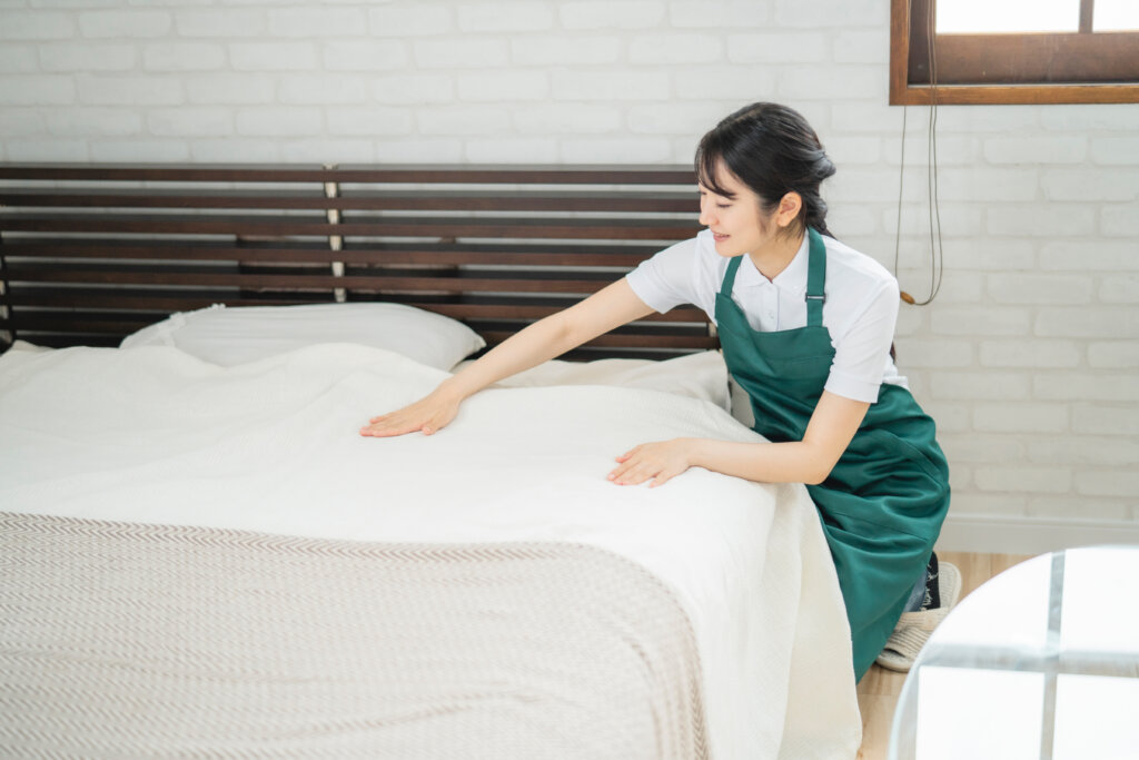 宿泊施設でベッドを整える女性スタッフ