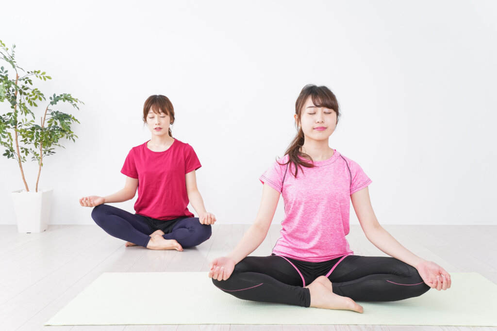 ヨガウェアを着た女性たちが室内で瞑想している様子