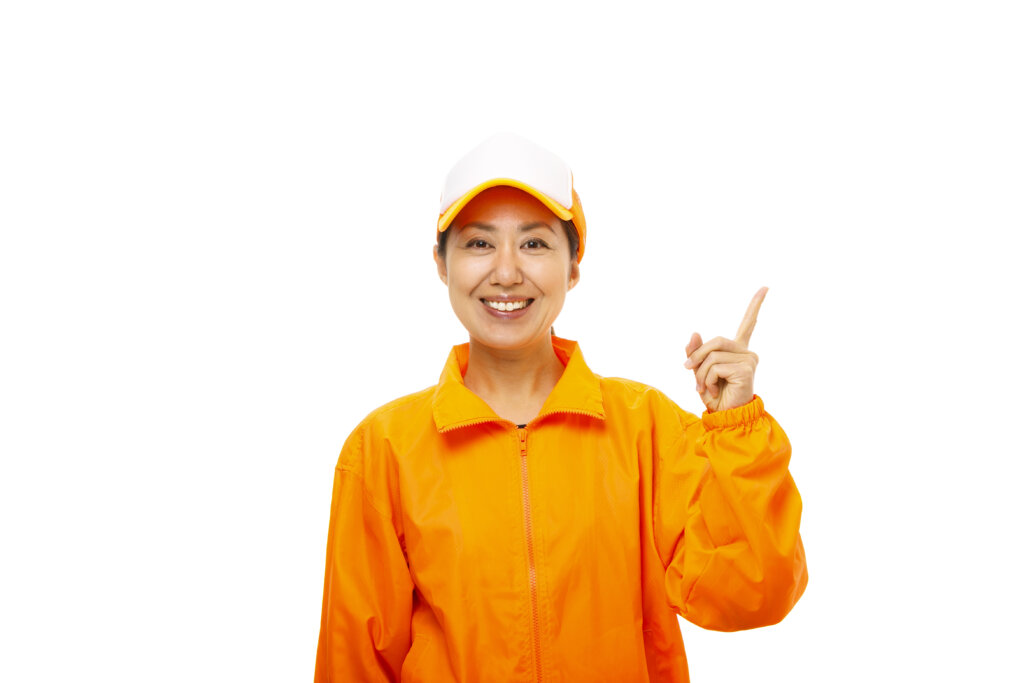 オレンジ色の制服を着た女性スタッフ、笑顔で案内を指さす