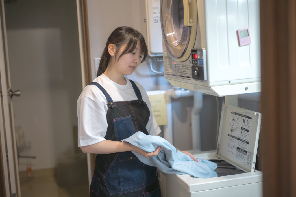 洗濯代行の作業中に洗濯機を操作する女性スタッフ