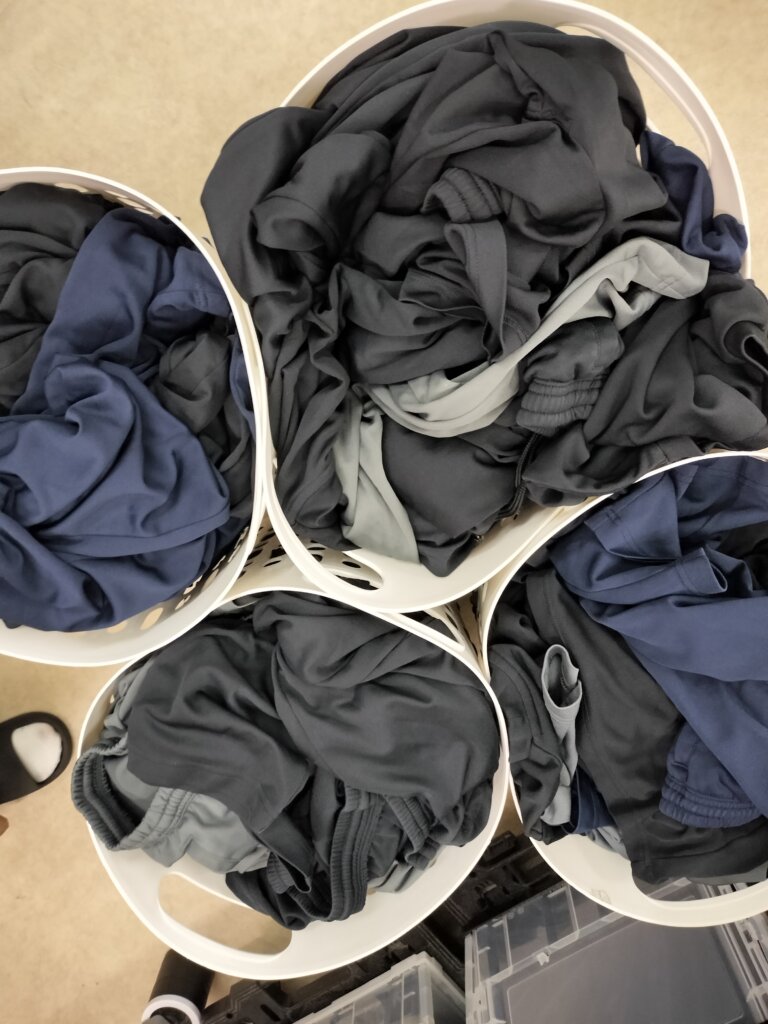 洗濯前のTシャツとスウェットが白いバスケットに入っている状態