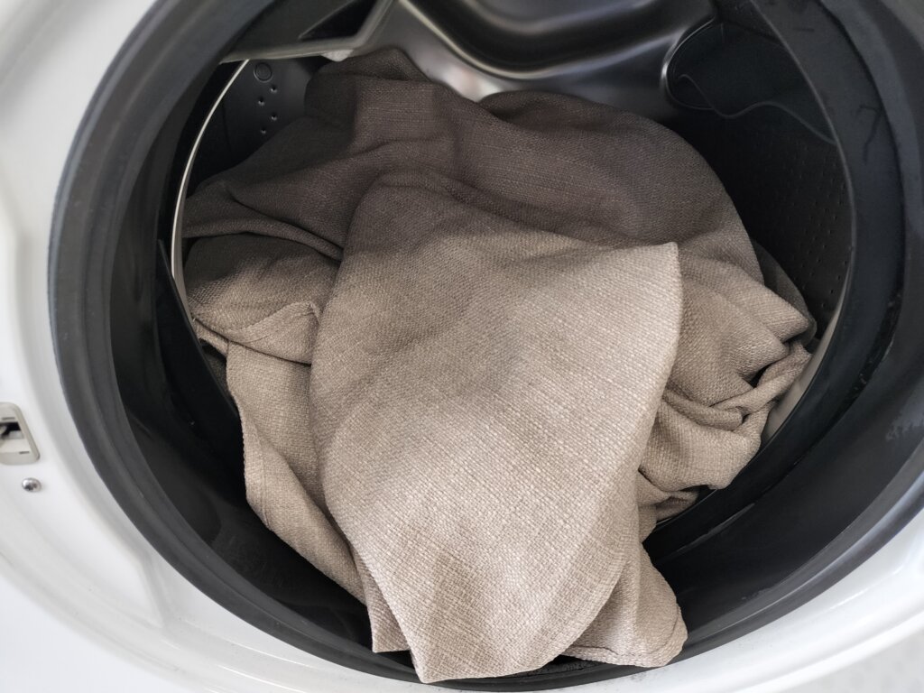 洗濯機に入ったベージュ色のテーブルクロス