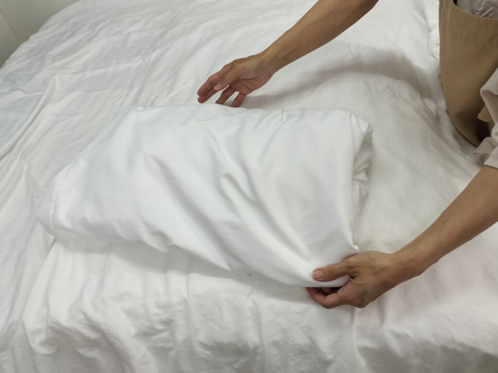 洗濯後のシーツやタオルをサイズごとにたたみ、納品前に仕分けたリネン
