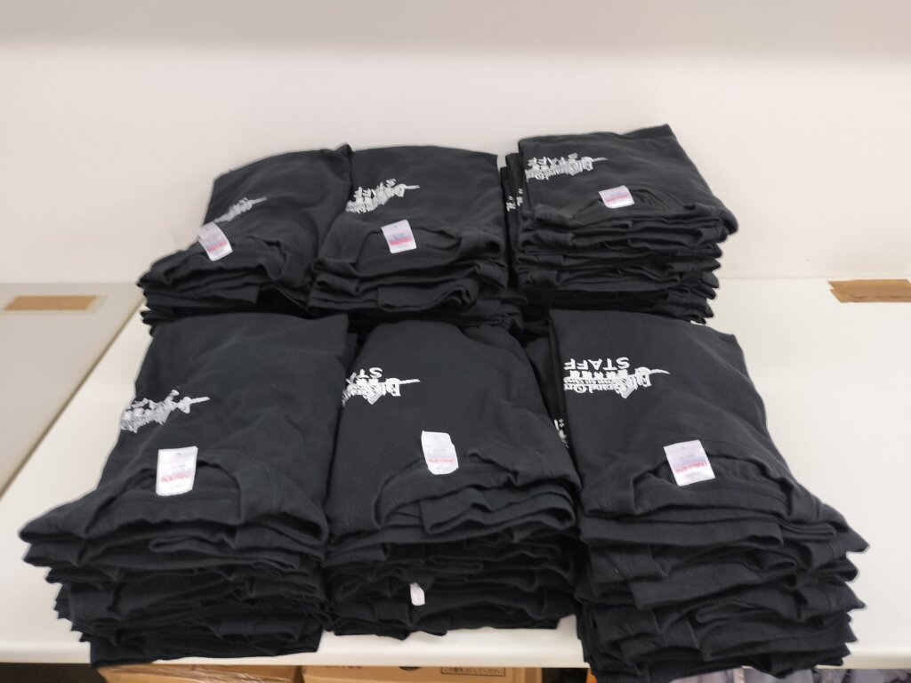 テーブルの上に並べられた大量のTシャツ(納品直前の状態)