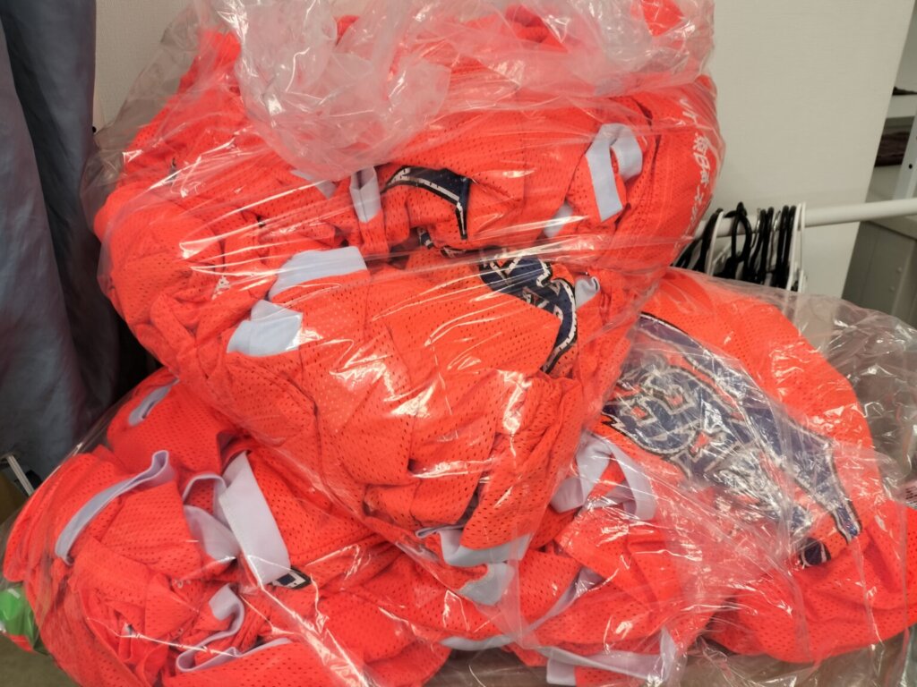 大量のオレンジ色ビブスが袋にまとめて積まれている様子