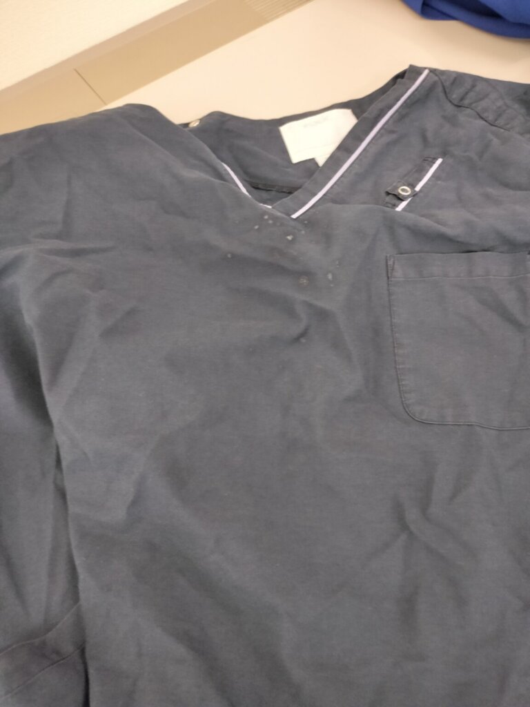 胸元に細かいシミが付着した医療用スクラブのアップ写真。
