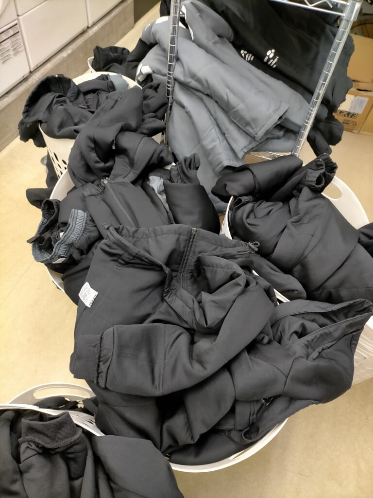 黒いベンチコートが大量に集荷され仕分けされている様子