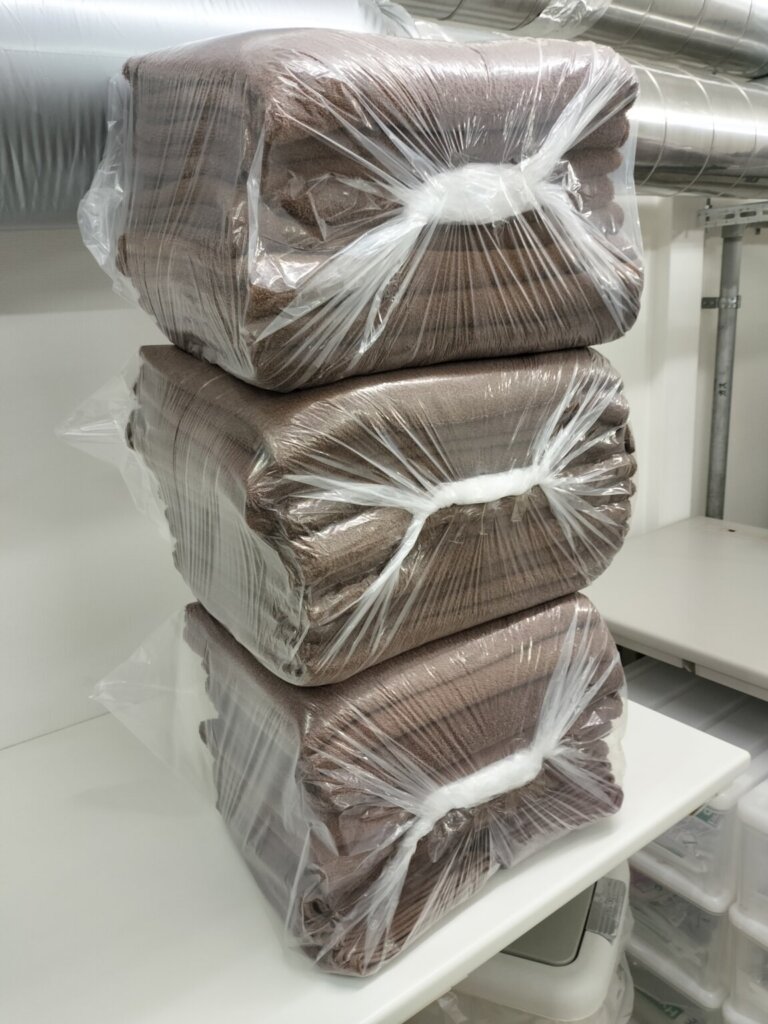 仕上げ後に整然と積まれたタオル類ビニール梱包済み