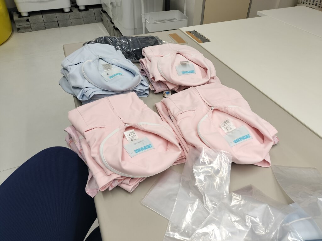 テーブルに並べられた複数の白衣の仕分け作業