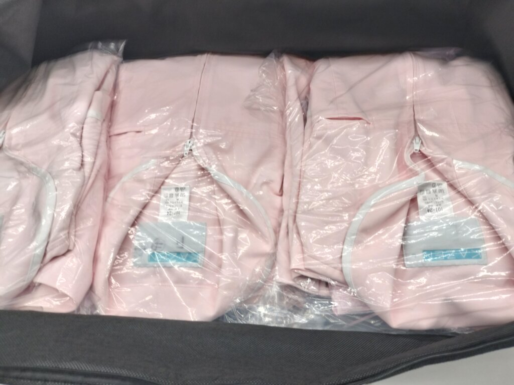 上下セットで個別包装された白衣をまとめて納品する様子