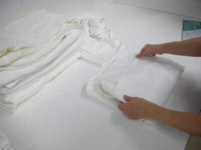 リネン類を手でたたんで仕上げてる様子