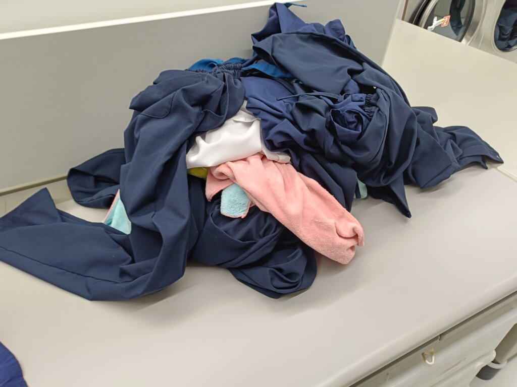 スクラブ、白衣、タオルが洗濯乾燥後たたみ台に乗せられる