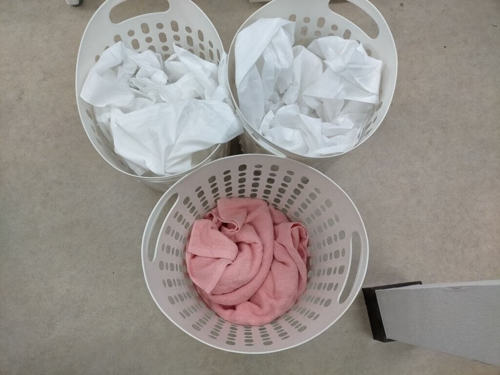 洗濯カゴにリネン類が仕分け、シーツ、タオルなど